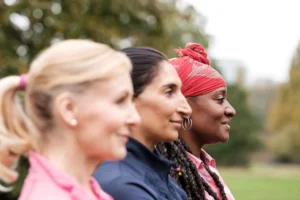 Three women smiling side by side outdoors in Leeds, representing diversity and community spirit for Doing Good Leeds charity work.