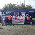 group of about 30 men at the powerleague football tournament with a northern man festival banner